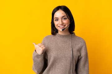 Young telemarketer woman isolated on yellow background pointing to the side to present a product - obrazy, fototapety, plakaty