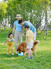 Happy family of four and pet dog playing in the park