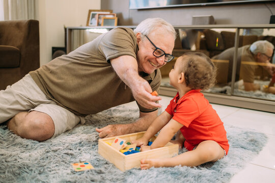Latino grandfather armless playing with his grandson on the living room floor. Disability concept