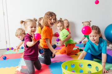 Happy kids throwing balls into plastic basket - 439152077