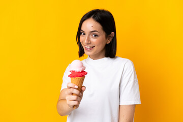 Young caucasian woman with a cornet ice cream isolated on yellow background with happy expression