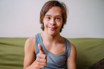 Close up portrait of friendly young Latino man with down syndrome doing thumbs up.