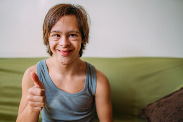 Close up portrait of friendly young Latino man with down syndrome doing thumbs up.