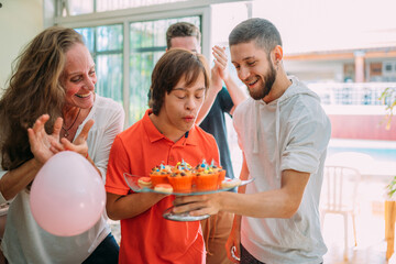 Young latino downs syndrome man celebrating birthday at home with cake