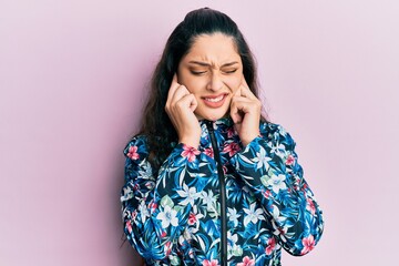 Beautiful middle eastern woman wearing casual floral jacket covering ears with fingers with annoyed expression for the noise of loud music. deaf concept.