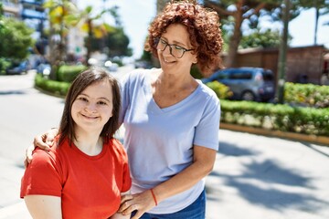 Mature mother and down syndorme daughter smiling happy and friendly outdoors