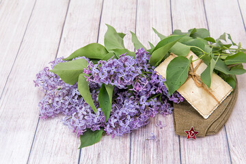 Victory Day. 9th May. A bouquet of lilacs, old photos and a soldier's cap / On the photo is a dummy...