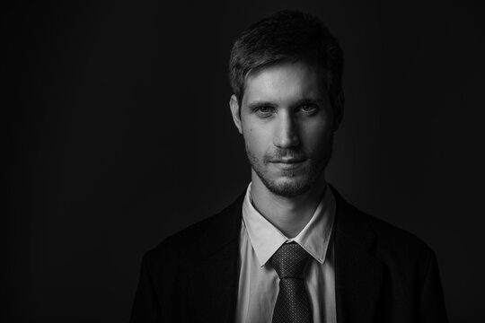 Young confident caucasian man in suit in black and white. Business concept