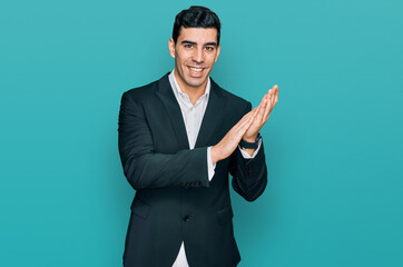 Handsome hispanic man wearing business clothes clapping and applauding happy and joyful, smiling...