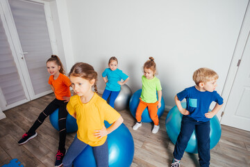 Cute kids balancing laying on large fitballs
