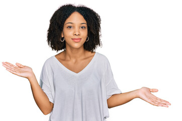 Young african american girl wearing casual clothes clueless and confused expression with arms and...