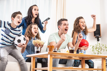 Raving fans cheering sports, as family of five watch football, match on the TV at home, screaming from joy
