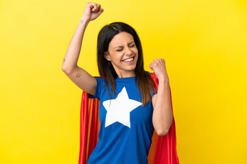 Woman isolated on yellow background in superhero costume and celebrating a victory © luismolinero