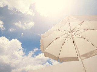 White beach umbrella against sunny sky.