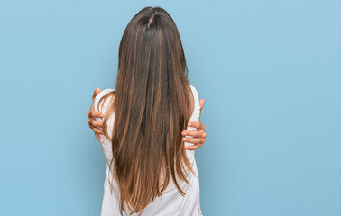 Young beautiful woman wearing casual clothes hugging oneself happy and positive from backwards....