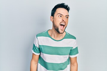 Young hispanic man wearing casual clothes angry and mad screaming frustrated and furious, shouting with anger. rage and aggressive concept.