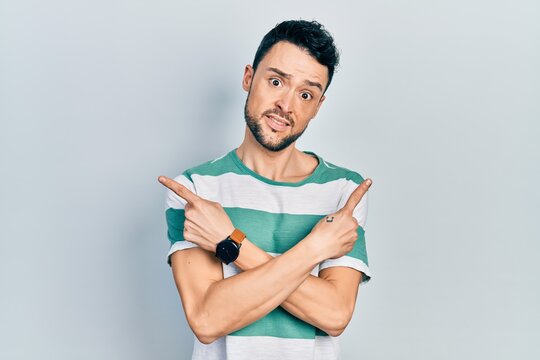 Young hispanic man wearing casual clothes pointing to both sides with fingers, different direction disagree
