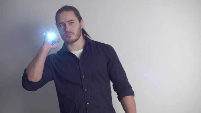 Security guard with a red beard and long hair, an athlete, shines with a flashlight