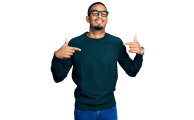 Naklejka premium Young african american man wearing casual clothes and glasses looking confident with smile on face, pointing oneself with fingers proud and happy.