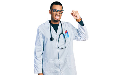 Fototapeta premium Young african american man wearing doctor uniform and stethoscope angry and mad raising fist frustrated and furious while shouting with anger. rage and aggressive concept.
