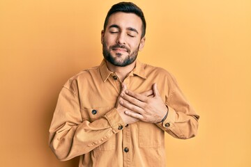 Young hispanic man wearing casual clothes smiling with hands on chest, eyes closed with grateful gesture on face. health concept.
