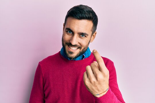 Young hispanic man wearing casual clothes beckoning come here gesture with hand inviting welcoming happy and smiling