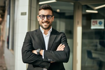 Young hispanic businessman with arms crossed smiling happy at the city.
