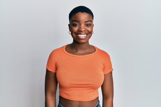 Young african american woman wearing casual orange t shirt with a happy and cool smile on face. lucky person.