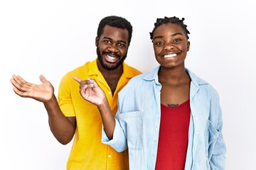 Young african american couple wearing casual clothes amazed and smiling to the camera while...