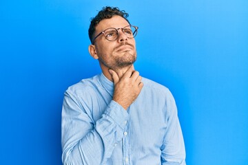 Young hispanic man wearing casual clothes and glasses touching painful neck, sore throat for flu, clod and infection