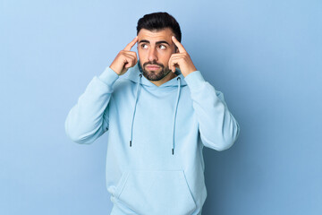 Caucasian man over isolated blue background having doubts and thinking
