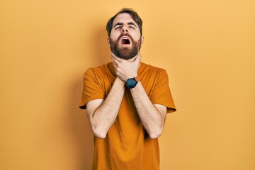 Caucasian man with beard wearing casual yellow t shirt shouting suffocate because painful strangle. health problem. asphyxiate and suicide concept.