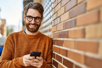 young caucasian man with beard  using smartphone outdoors on a sunny day
