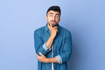 Caucasian man over isolated blue background having doubts while looking up