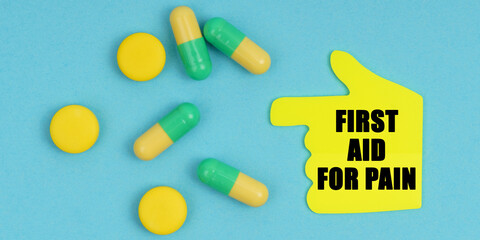 On a blue background, there are pills and a hand-sticker with the inscription - First aid for pain