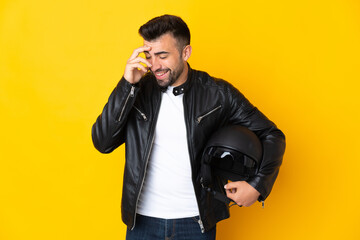 Caucasian man with a motorcycle helmet over isolated yellow background laughing