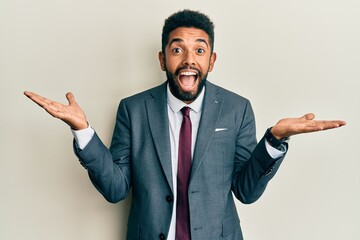 Handsome hispanic man with beard wearing business suit and tie celebrating crazy and amazed for...