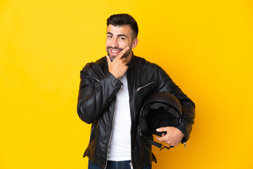 Caucasian man with a motorcycle helmet over isolated yellow background happy and smiling