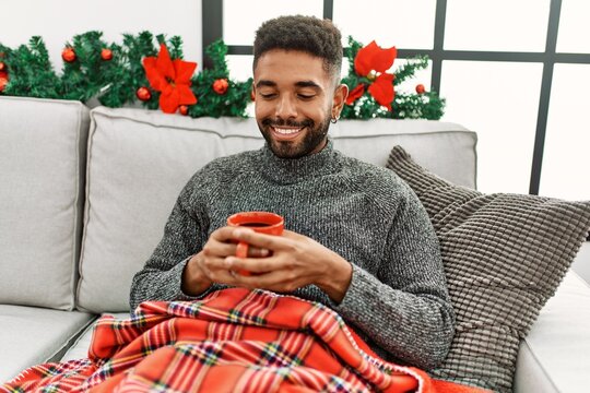 Young african american man drinking coffee celebrating christmas at home.