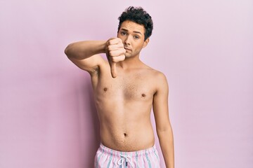 Fototapeta premium Young handsome man wearing swimwear shirtless looking unhappy and angry showing rejection and negative with thumbs down gesture. bad expression.