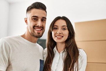 Young hispanic couple smiling happy and hugging at new home.