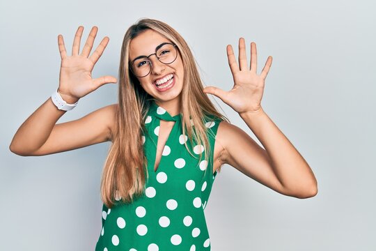 Beautiful hispanic woman wearing elegant shirt and glasses showing and pointing up with fingers number ten while smiling confident and happy.