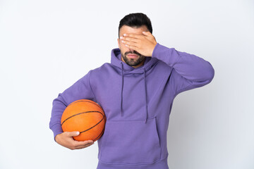 Man playing basketball over isolated white wall covering eyes by hands. Do not want to see something