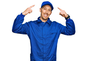 Bald man with beard wearing builder jumpsuit uniform smiling pointing to head with both hands finger, great idea or thought, good memory