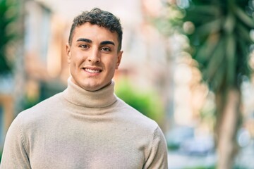 Young hispanic man smiling happy standing at the city.