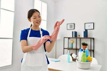 Young chinese housewife put in gloves at home.