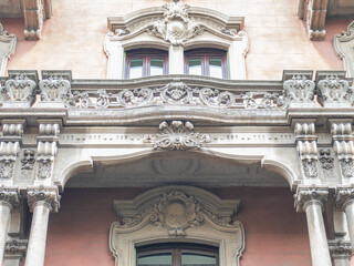 low arched window on balcony with molded concrete decorations. 20th century building in Milan. Italy