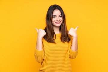Young caucasian woman isolated on yellow background with thumbs up gesture and smiling