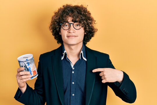 Handsome young man holding piggy bank pointing finger to one self smiling happy and proud
