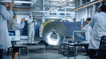Technician in Protective Suit Finishes Satellite Construction, Team of Scientists Applaud and Cheer for Successful. Aerospace Agency Manufacturing Facility: Scientists Assembling Spacecraft. 